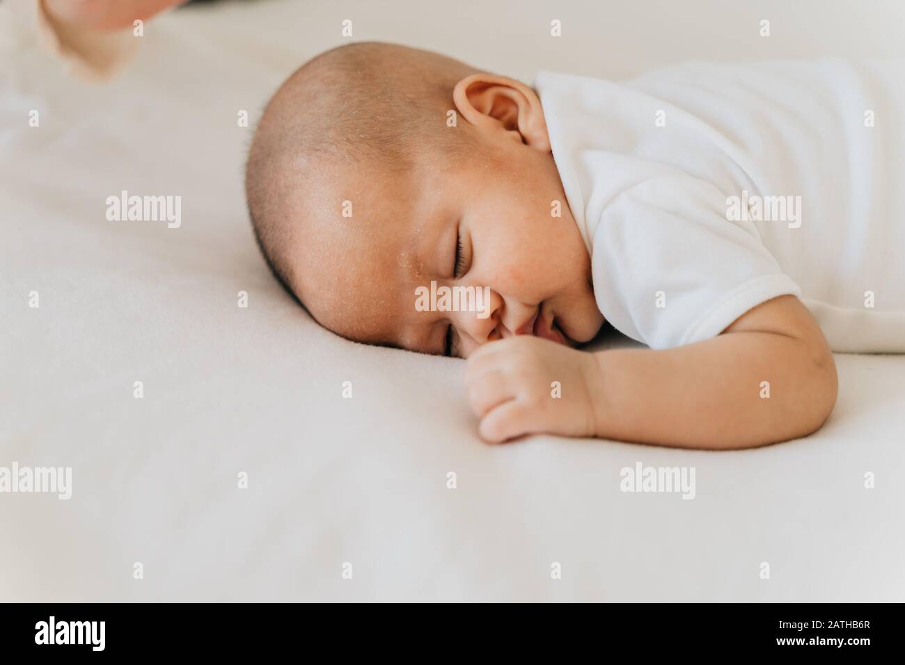 Newborn baby kid sleeping on his stomach on bed at home. Asian child