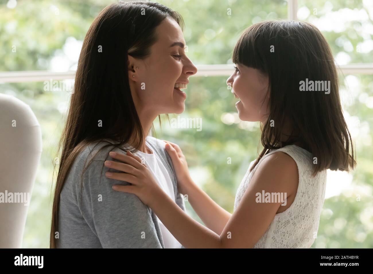 Overjoyed little daughter feel happy talking with mom Stock Photo