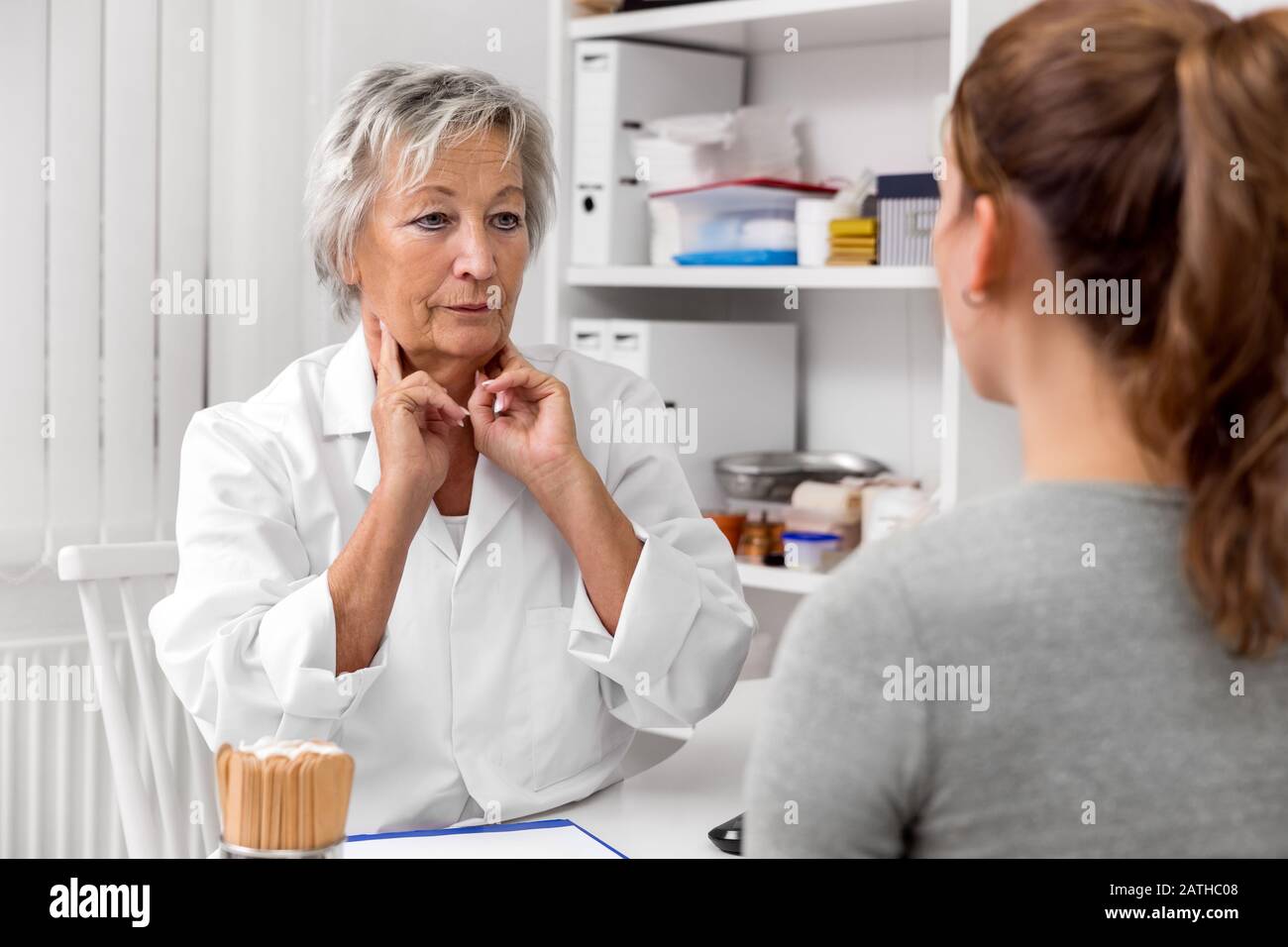 Female doctor holding her lymph node on the neck, exhibition and demonstration to a patient Stock Photo