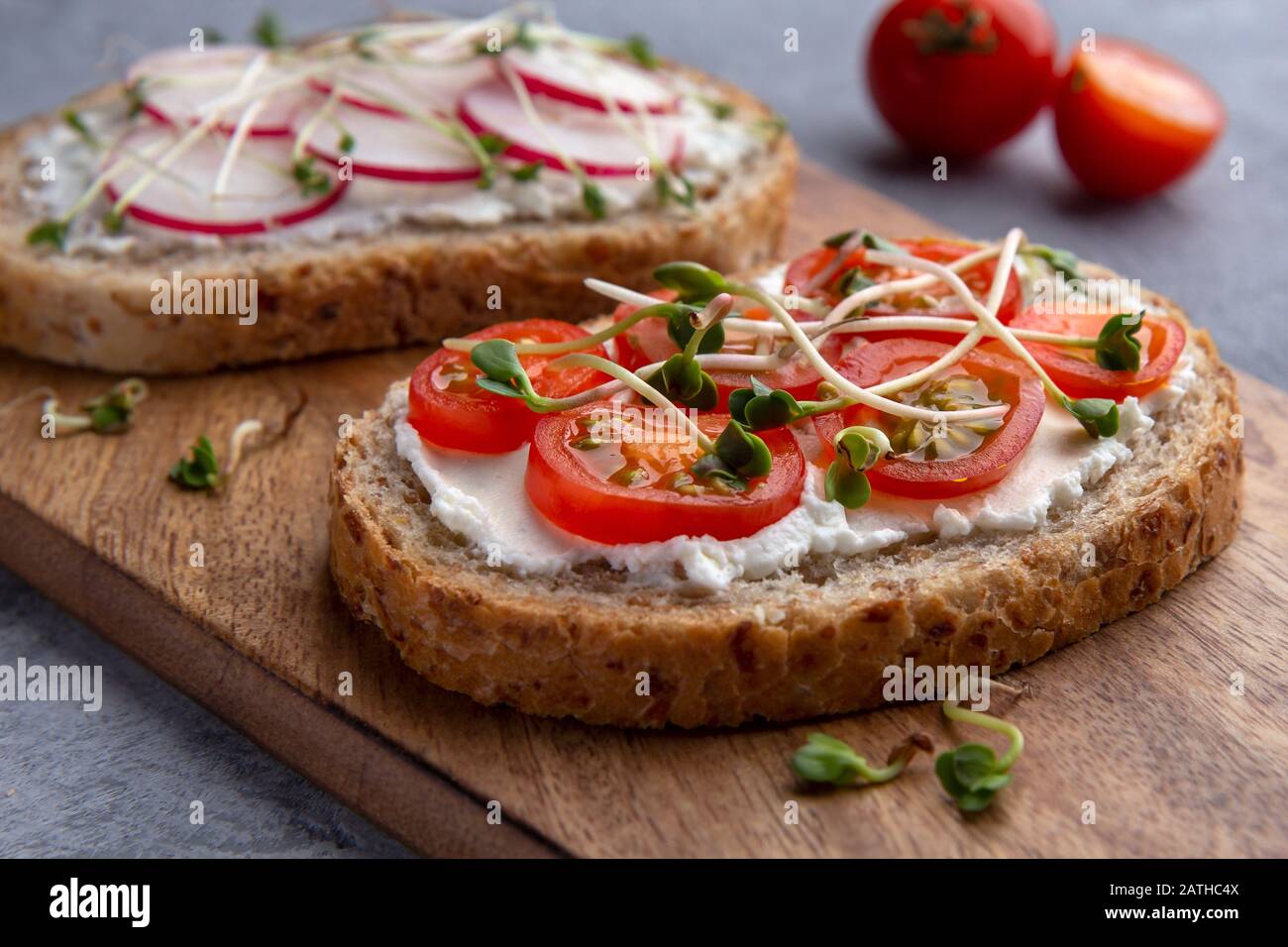 Close-up of a sandwich with tomatoes, microgreens and grain bread on a grey background Stock Photo