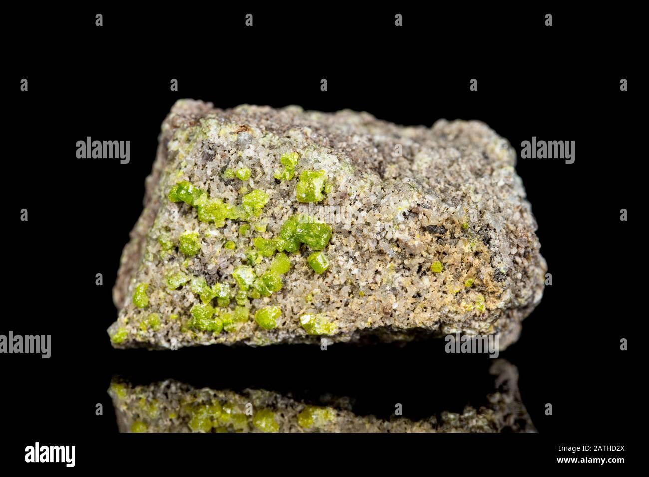 Raw peridot or olivine mineral stone in front of black background
