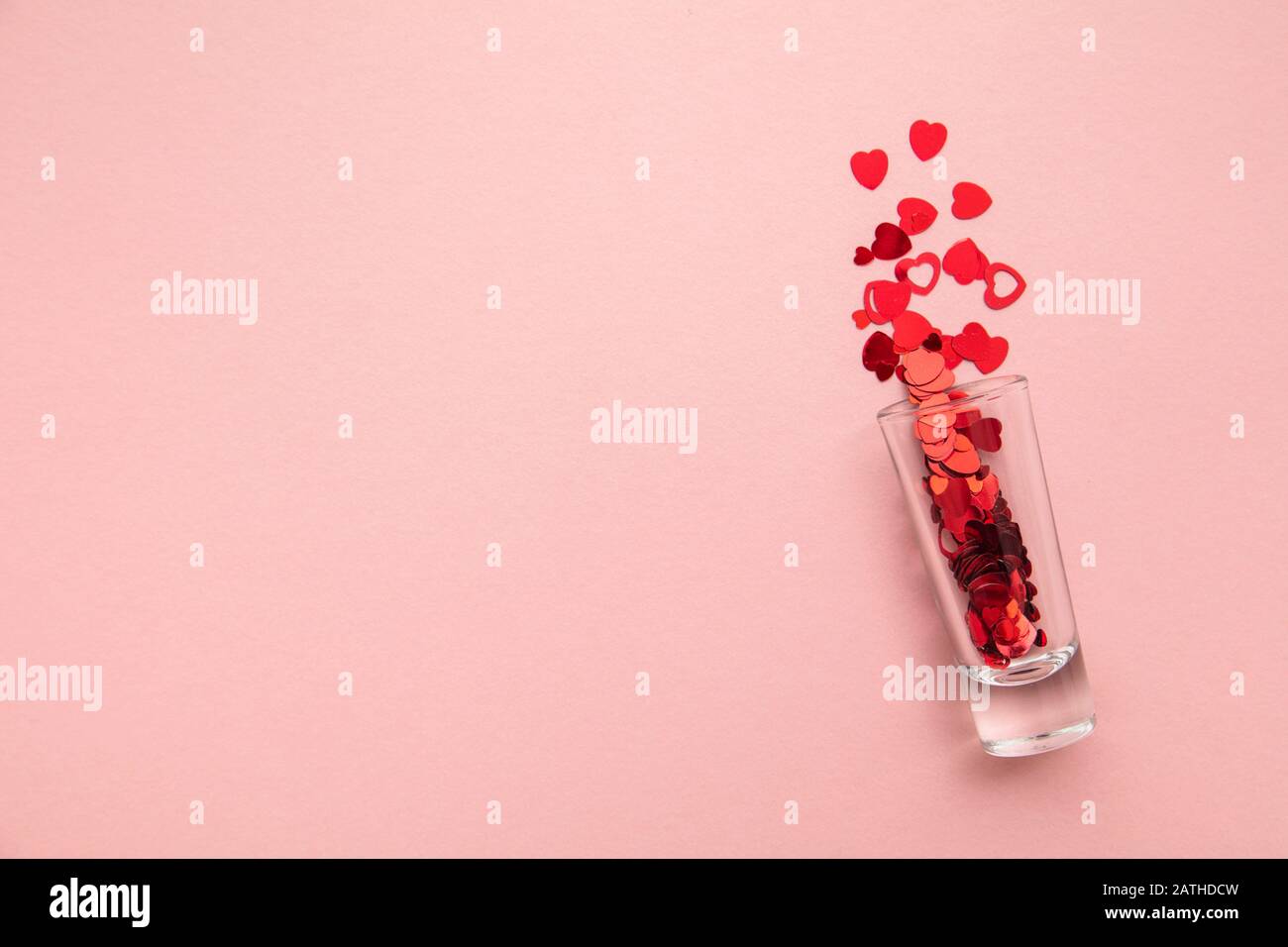 Valentine's day shots. Shot glass with heart confetti on pastel pink background Stock Photo