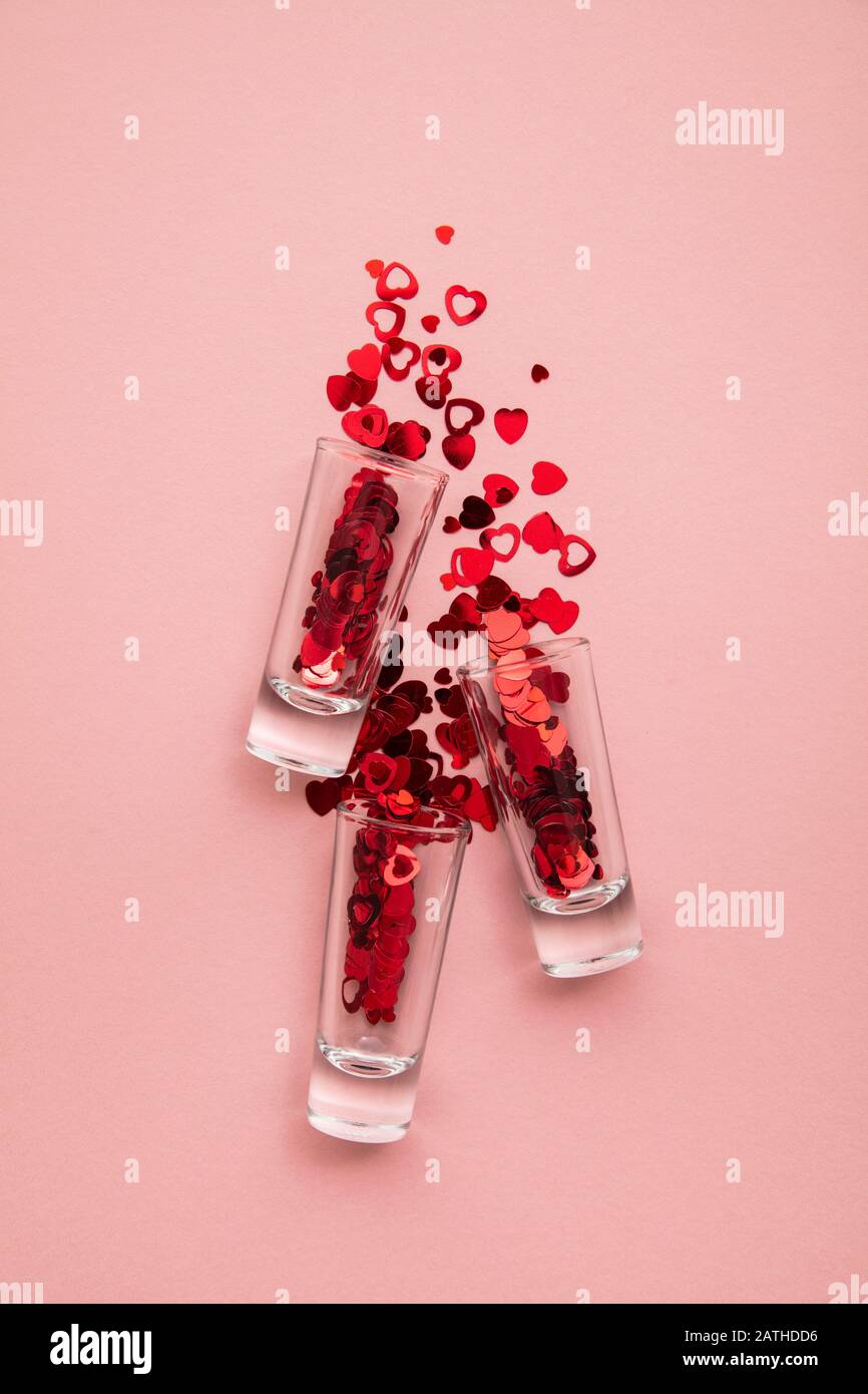 Valentine's day shots. Shot glass with heart confetti on pastel pink background Stock Photo