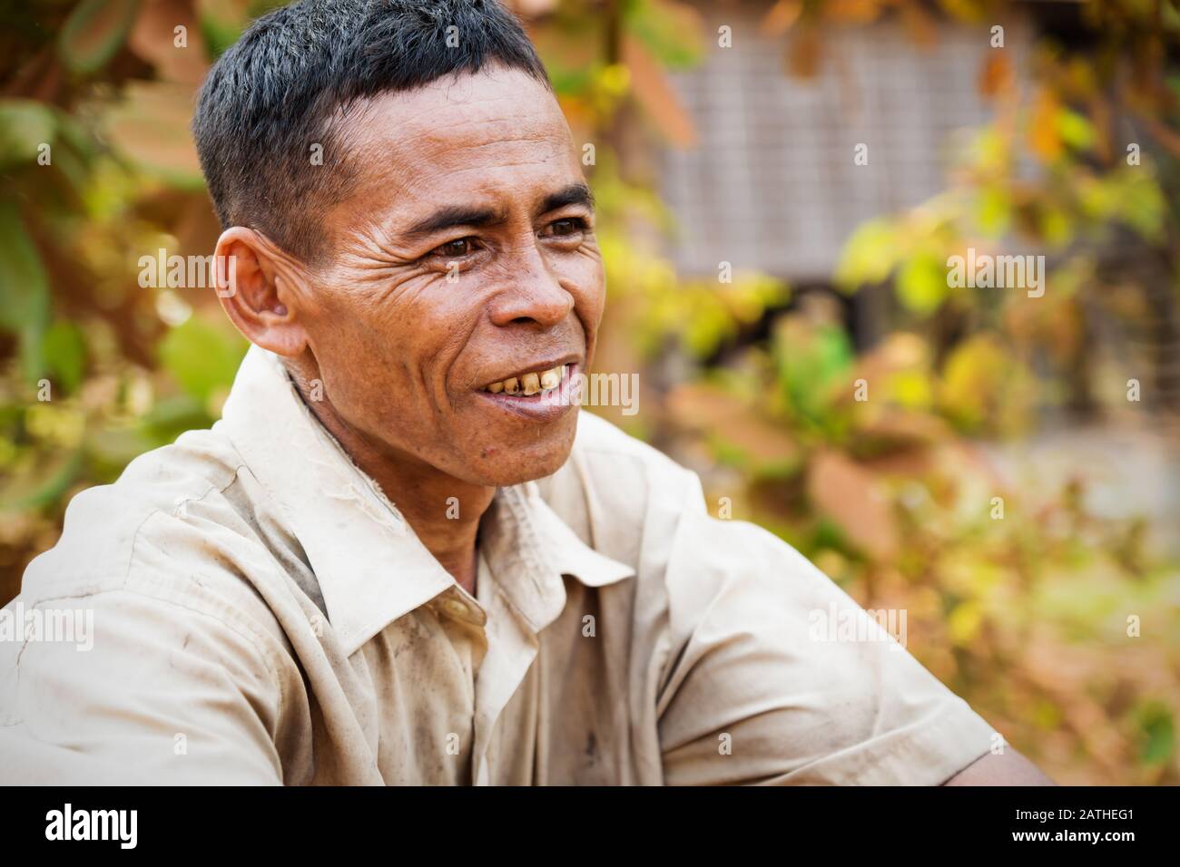 Puok, Siem Reap Province, Cambodia - 4 April 2013: Cambodian local man smiling with orange leaves background Stock Photo