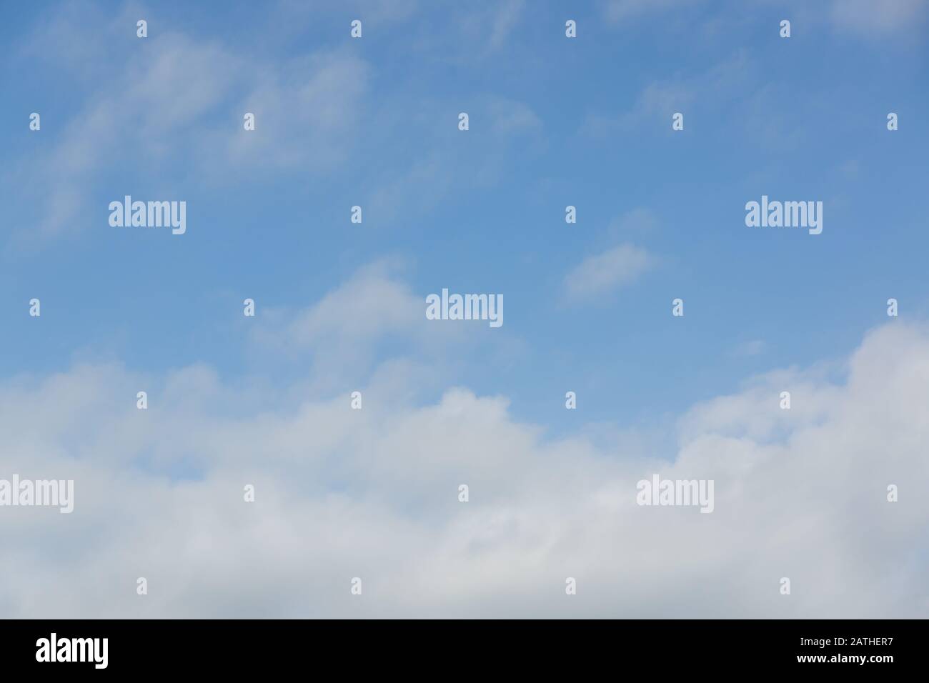Hazy blue summer sky with whispy white cumulus clouds Stock Photo
