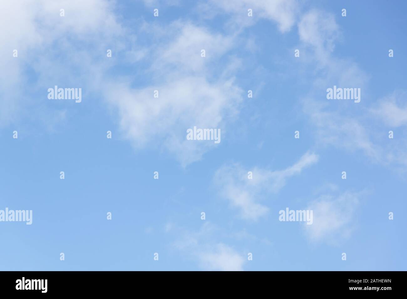Hazy blue summer sky with whispy white cumulus clouds Stock Photo