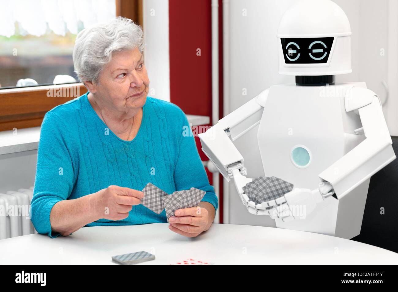 ambient assisted living service robot is playing a card game with a senior adult woman, concepts like robotic caregiver in the household or old folks Stock Photo