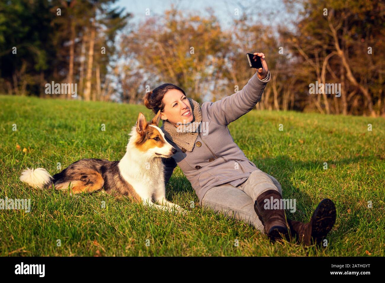Woman makes a selfie with her dog on a green meadow, memory picture ...
