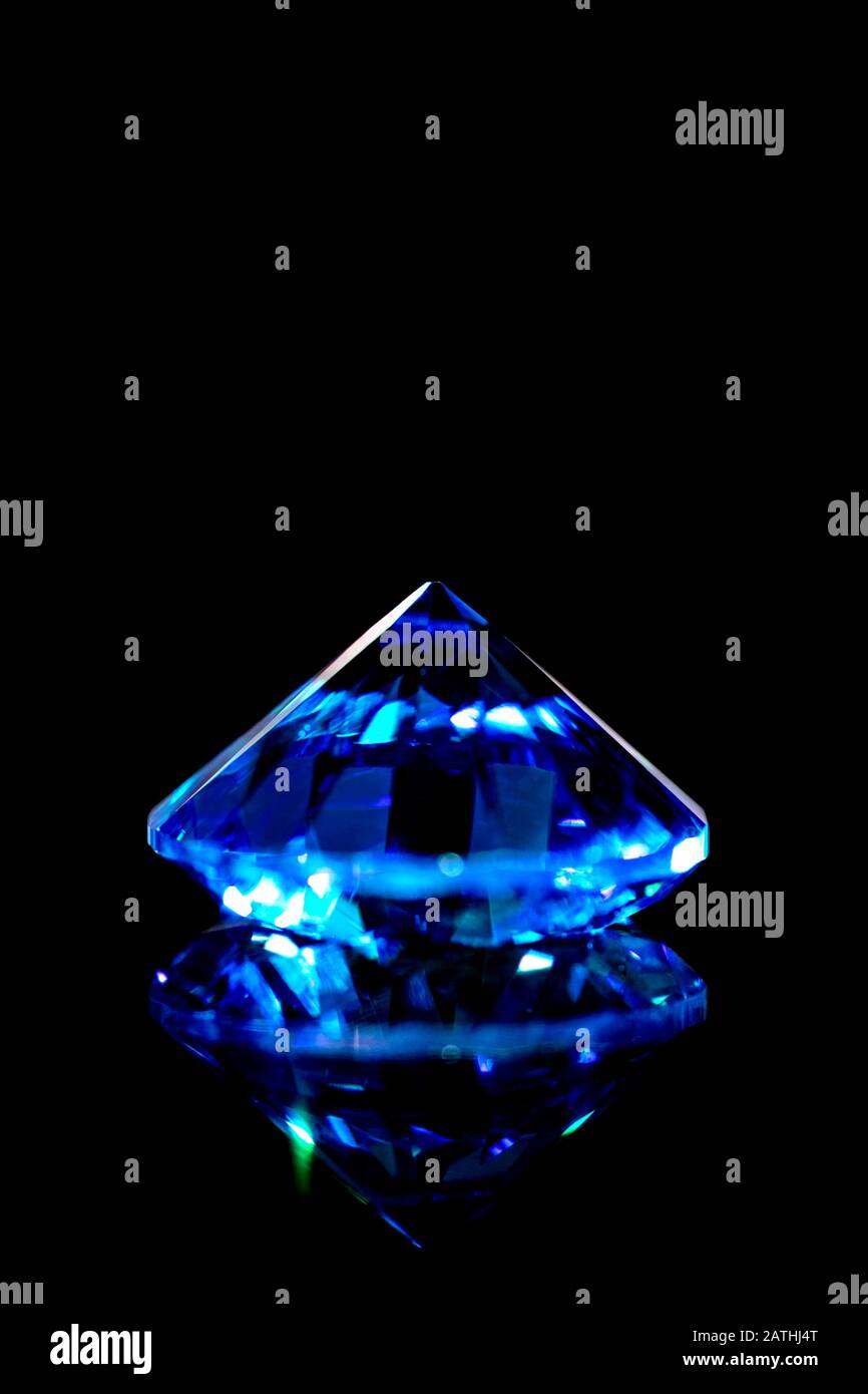 Blue sapphire in front of black background, brilliant cut, closeup Stock Photo