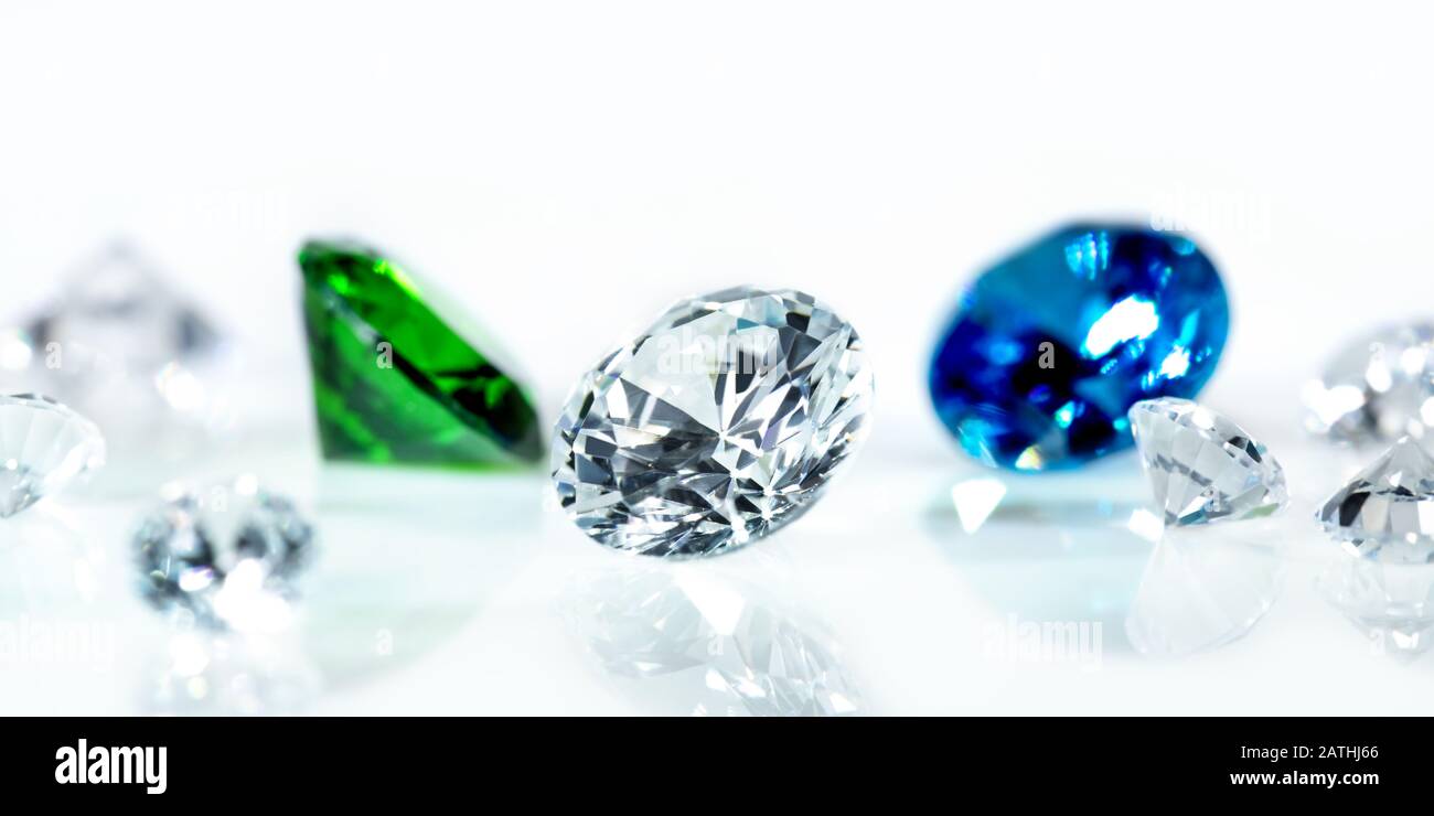Flawless diamonds, blue sapphire and a green emerald in front of white background, banner Stock Photo