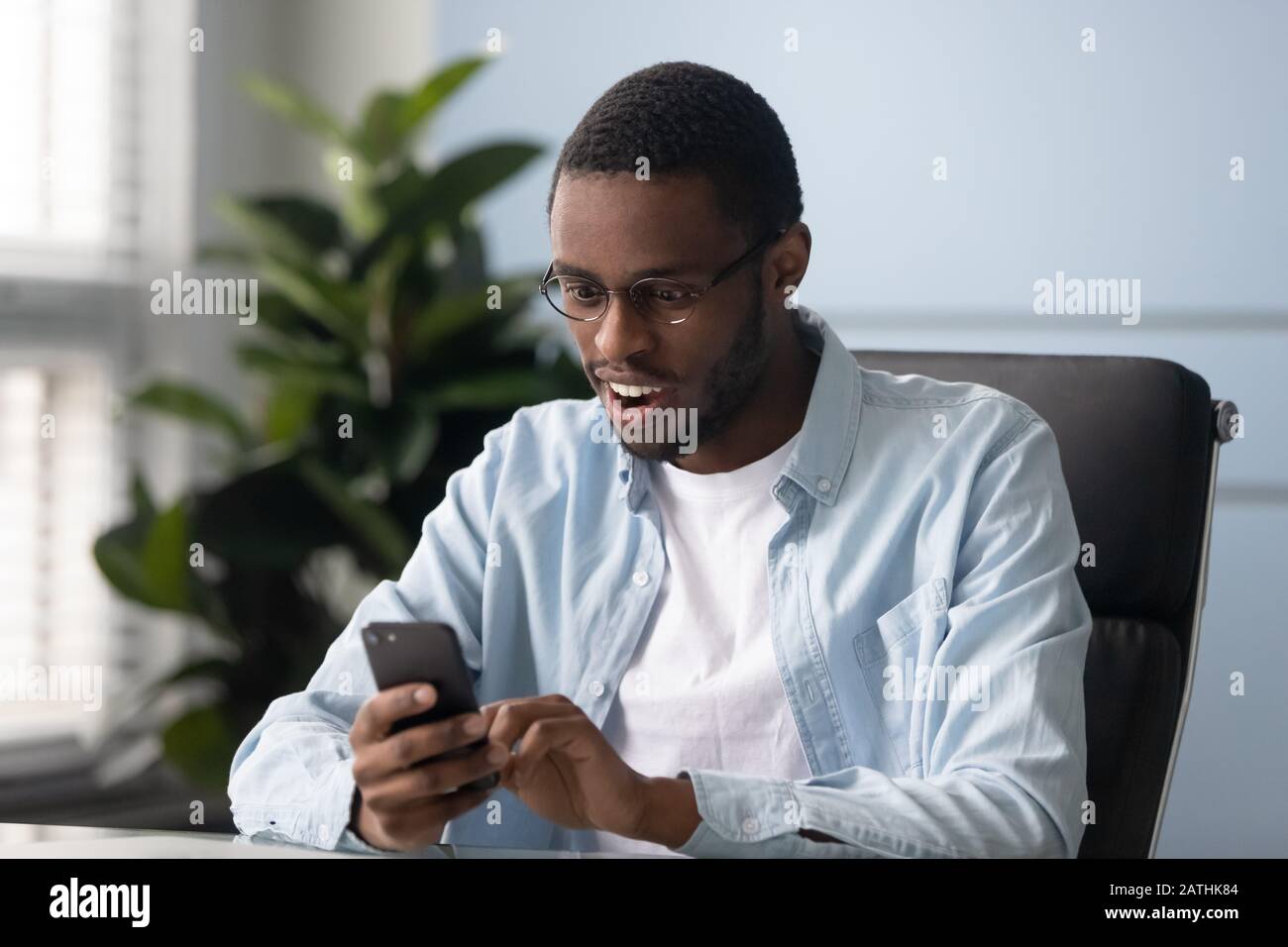 African ethnicity guy holding smartphone read received message feels surprised Stock Photo