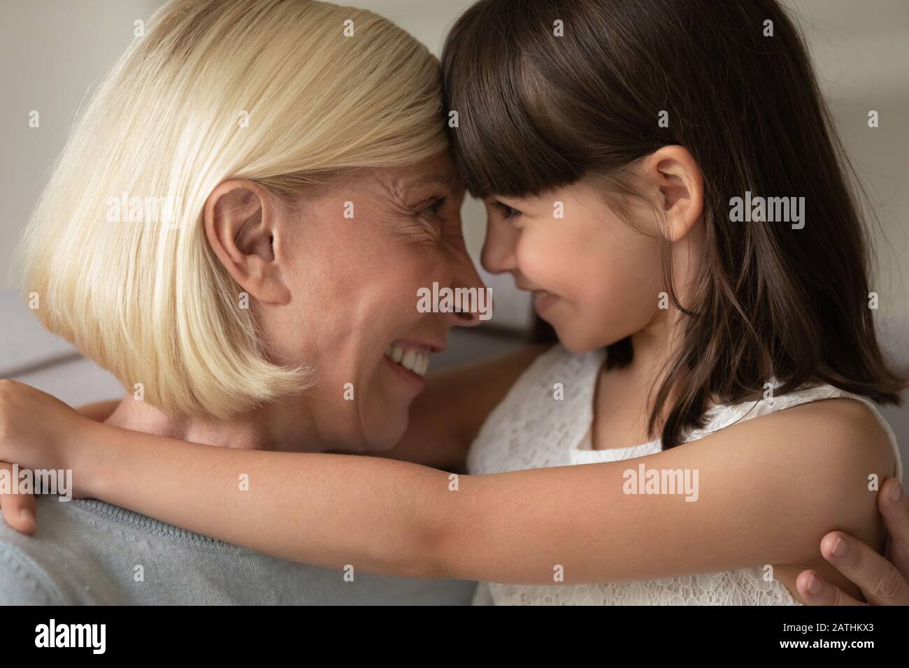 Smiling grandmother and little granddaughter hug looking in eyes Stock Photo