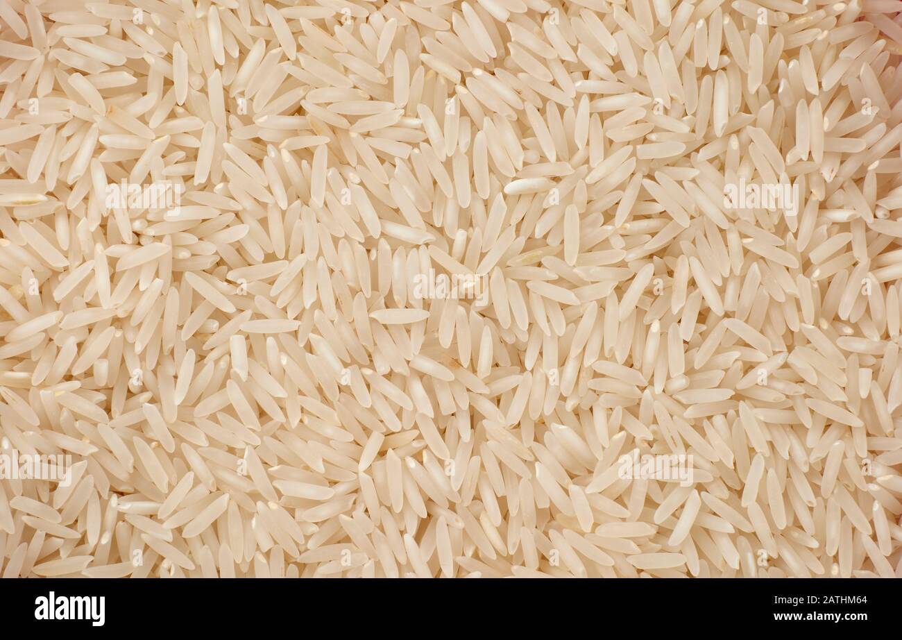 Large quantity of dry uncooked basmati rice lying on flat surface Stock
