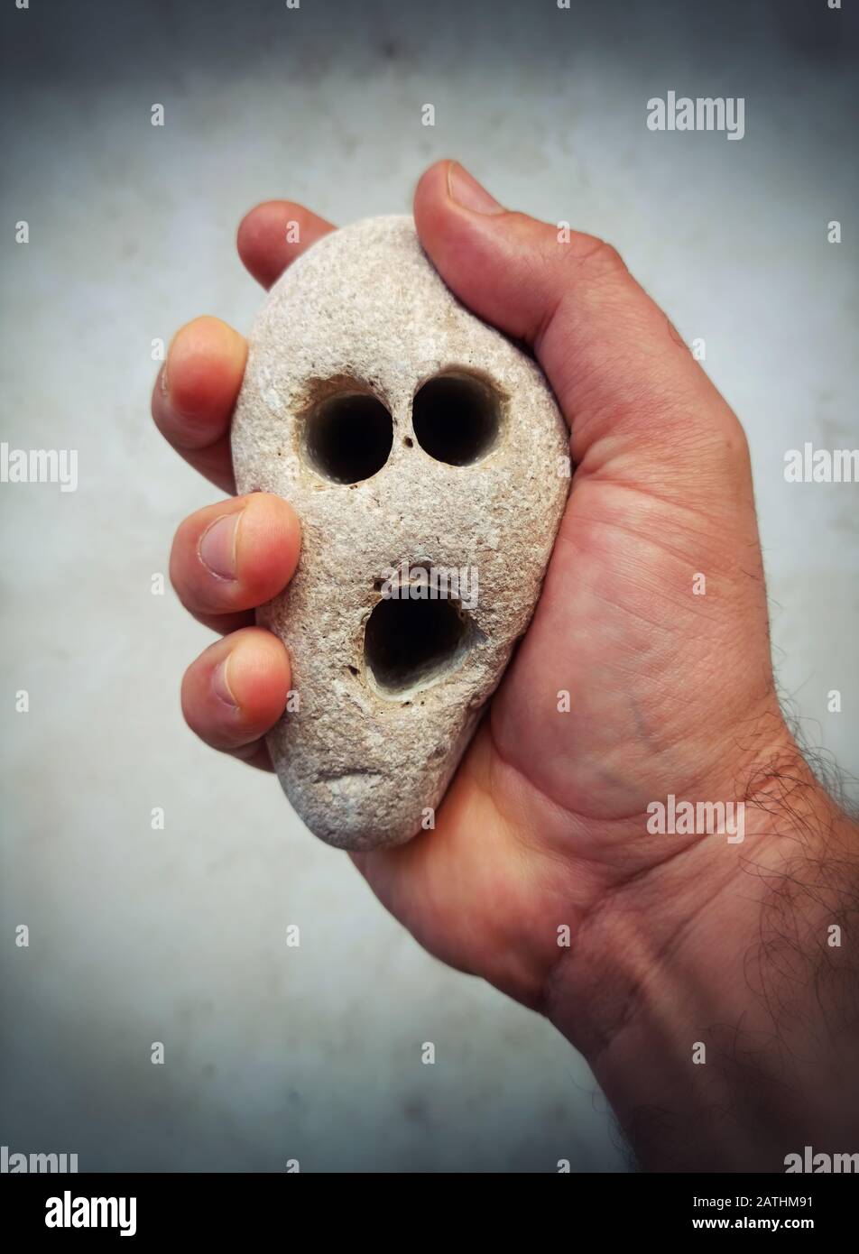 Man is holding a stone which look like a screaming face. Stock Photo