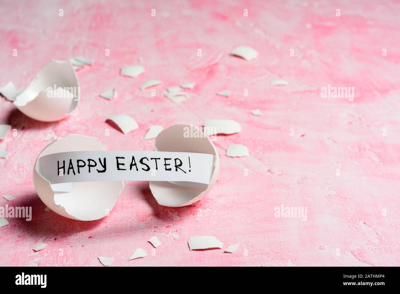 Cracked egg with text HAPPY EASTER on pink background. Copy space Stock Photo
