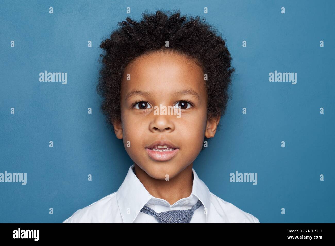 Little black kid boy student on blue background close up portrait Stock Photo