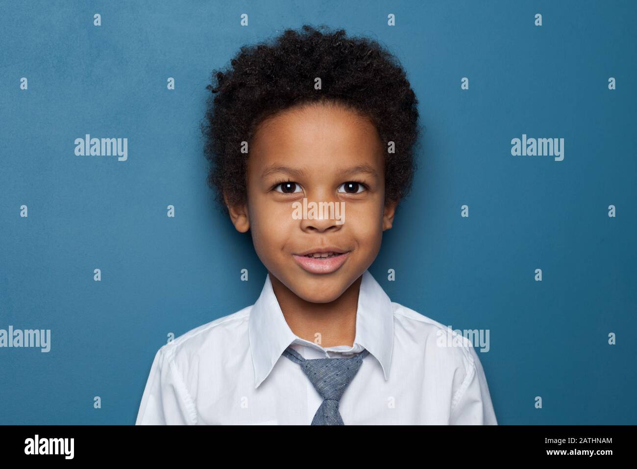 Cute curious African American child schoolboy student 6 years old on blue backgroung. Black kid boy portrait Stock Photo