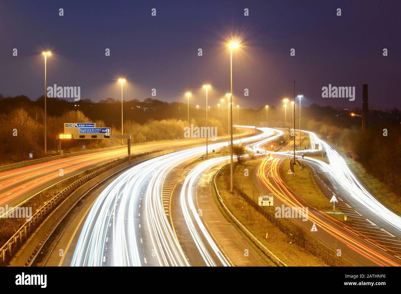 Junction 26 of the M60 ring road, also known as the 'Bredbury Scissors' at the evening rush hour with light trails from traffic. UK road, intersection Stock Photo
