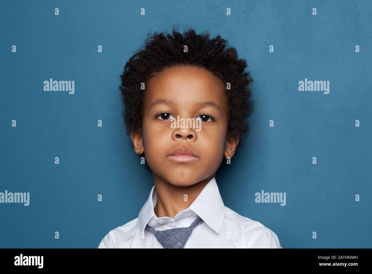 Portrait of curious smart black child boy student on blue background. African American kid pupil 6 years old Stock Photo