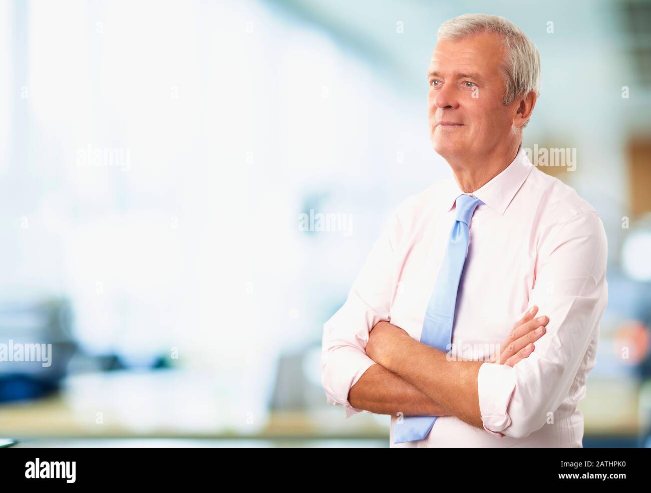 Portrait of a senior man standing with arms crossed indoor Stock Photo ...
