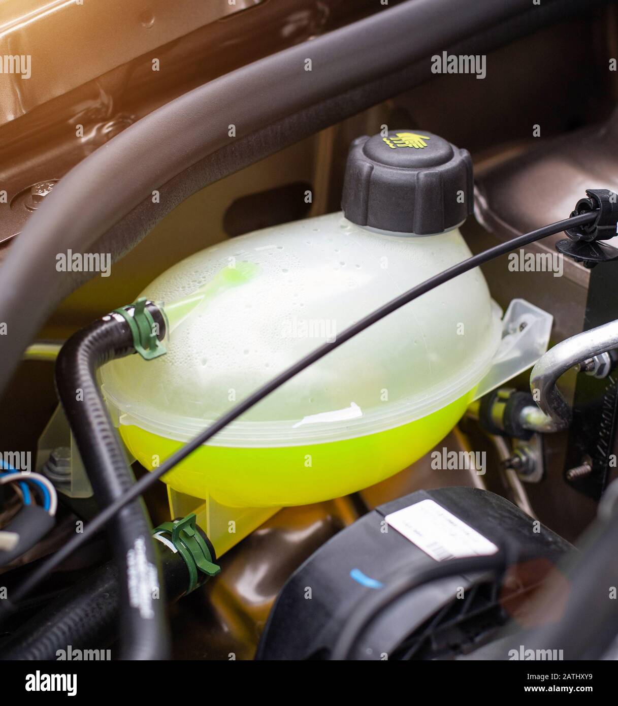Car reservoir for filling coolant. Yellow antifreeze in the expansion tank, freezing temperature concept in winter, transportation Stock Photo