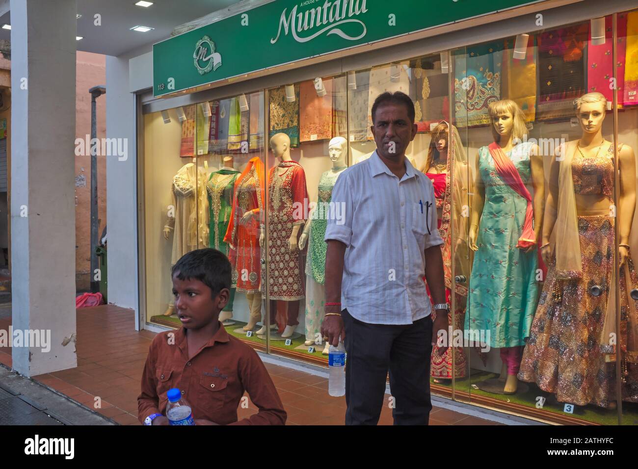 An ethnic Indian father and son pass by a shop selling Indian traditional attire; Little India area, Singapore Stock Photo