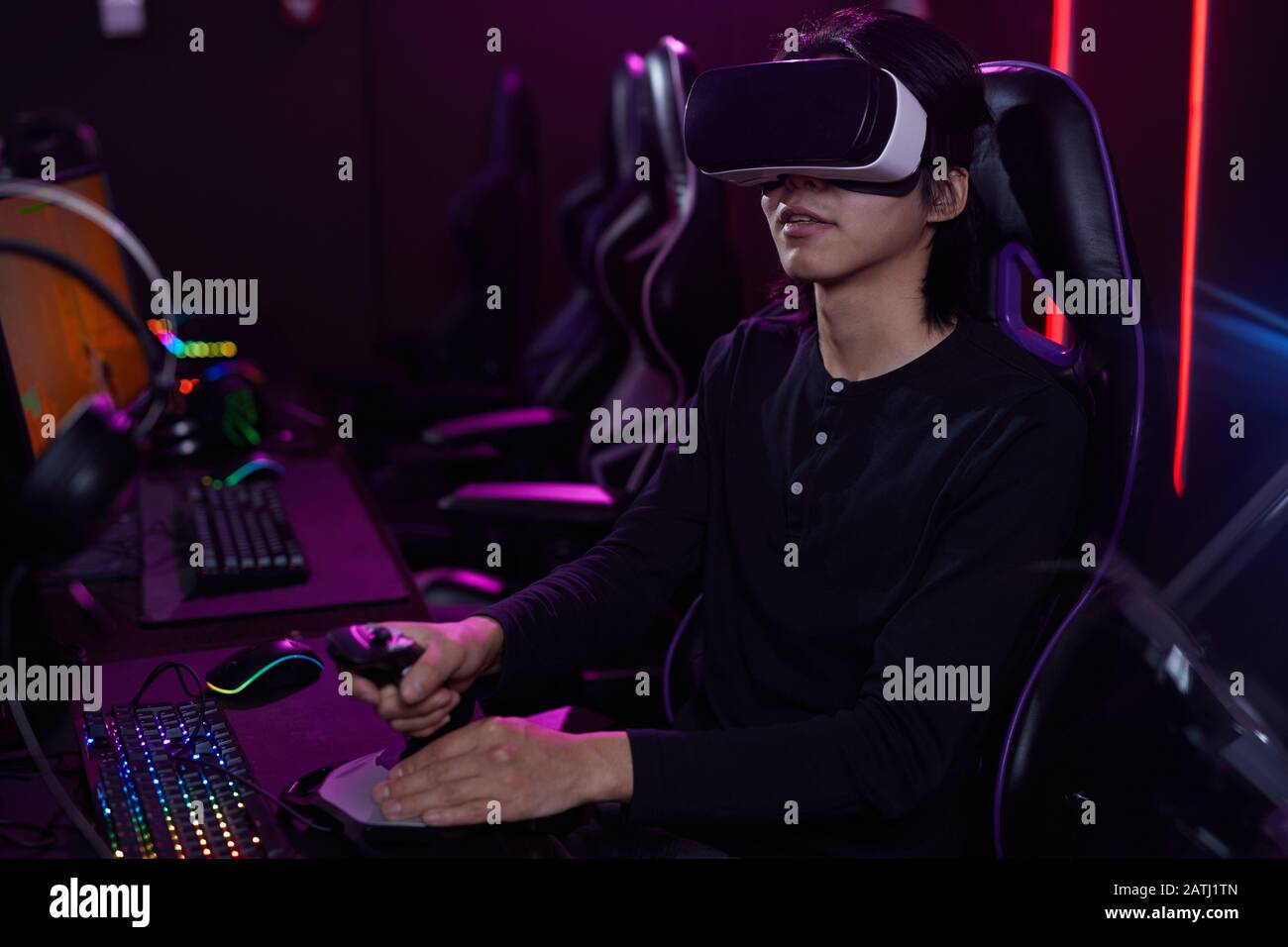 Portrait of young Asian man wearing VR headset while playing videogames ...