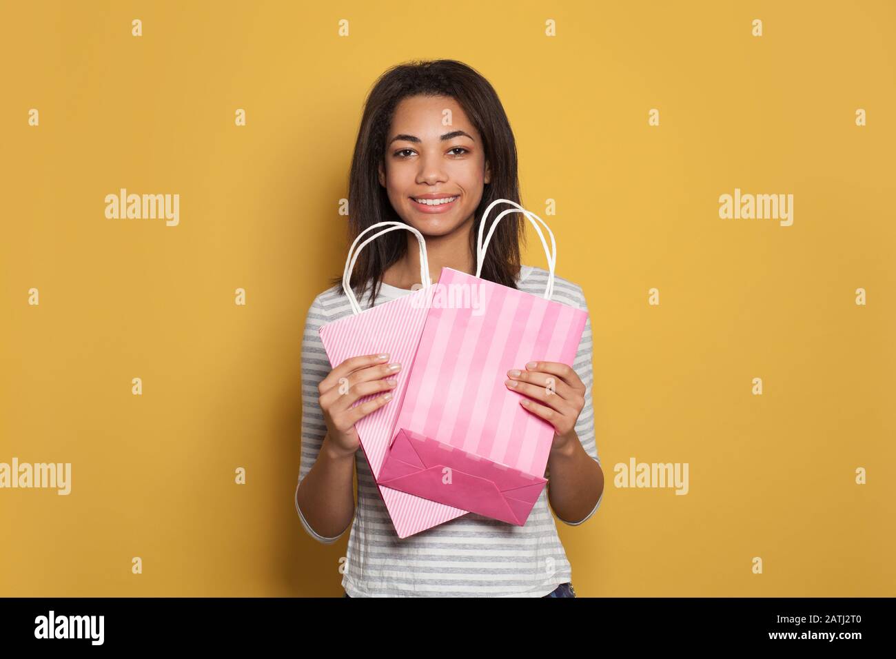 Pretty black woman holding pink shopping bags and smiling Stock Photo ...