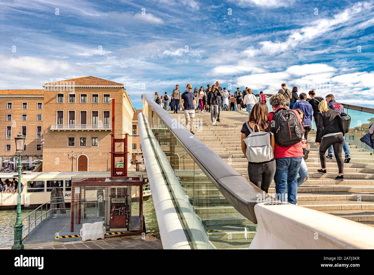 People walking across The Ponte delle Costituzione or Constitution Bridge in Venice , a glass and steel bridge which crosses The Grand Canal ,Venice Stock Photo