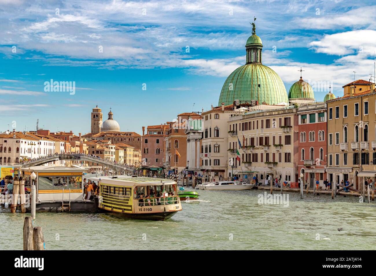 Vaporetto or water buses on The Grand Canal near Santa Lucia Station with the green dome of San Simeone Piccolo Church dominating the skyline ,Venice Stock Photo