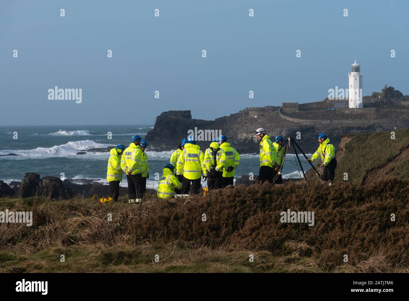 Coastguard search and rescue team in bright yellow high viz practicing abseils & retrieving on the wet windy cliffs at Gwithian nr. Godrevy lighthouse Stock Photo