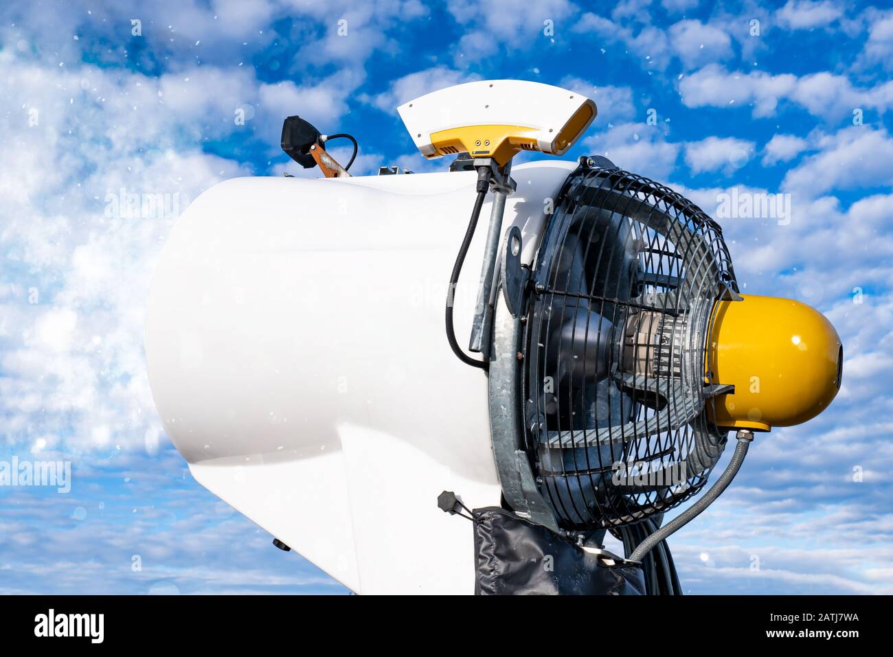 Close up of a snow cannon. Snow blows on the ski slopes. Blue sky with clouds. Stock Photo