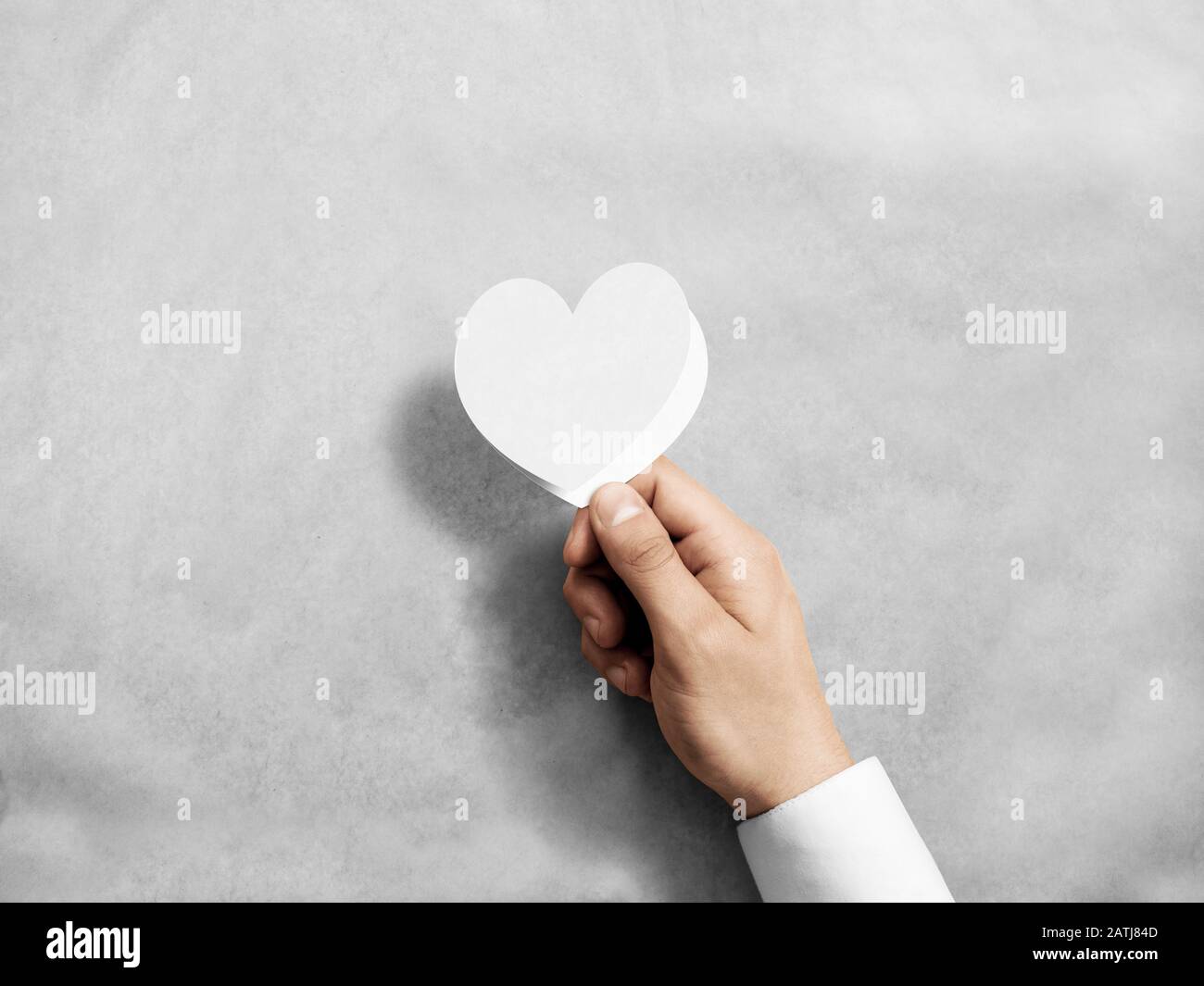 Hand holding blank white valentine's card mockup. Arm opening paper love invitation, design mock up. Holiday greeting postcard presentation. Person sh Stock Photo