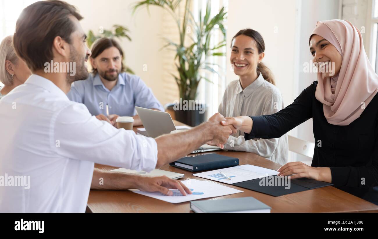 Smiling multiracial businesspeople handshake greeting at meeting Stock Photo