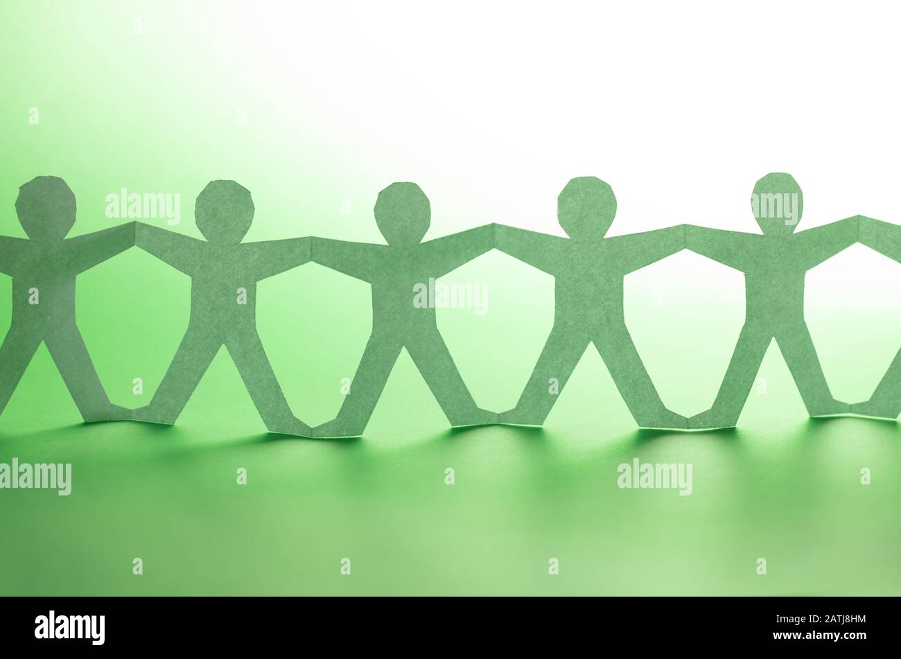 Team of paper chain people. Human chain with light and shadow on green backgorund. Stock Photo