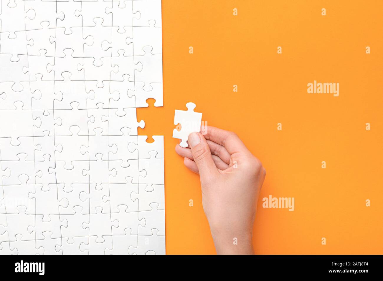 Hand put the last piece of jigsaw puzzle. Complete the mission. Business concept. Stock Photo