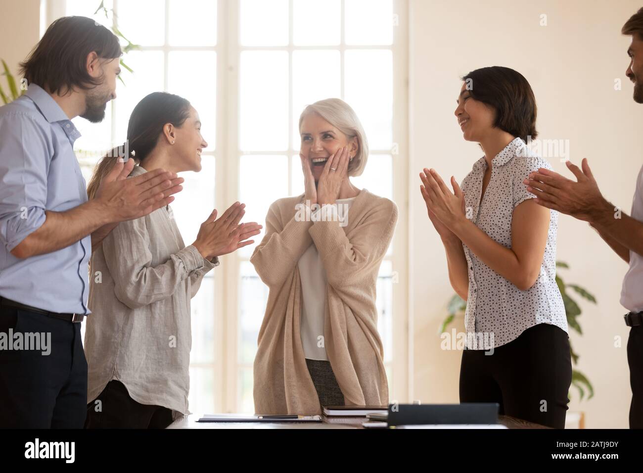 Happy colleagues clap hands greeting businesswoman with success Stock Photo