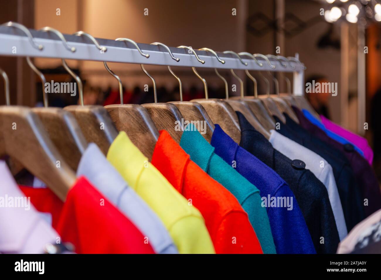Closeup colorful male, female clothes in boutique hanging on hangers