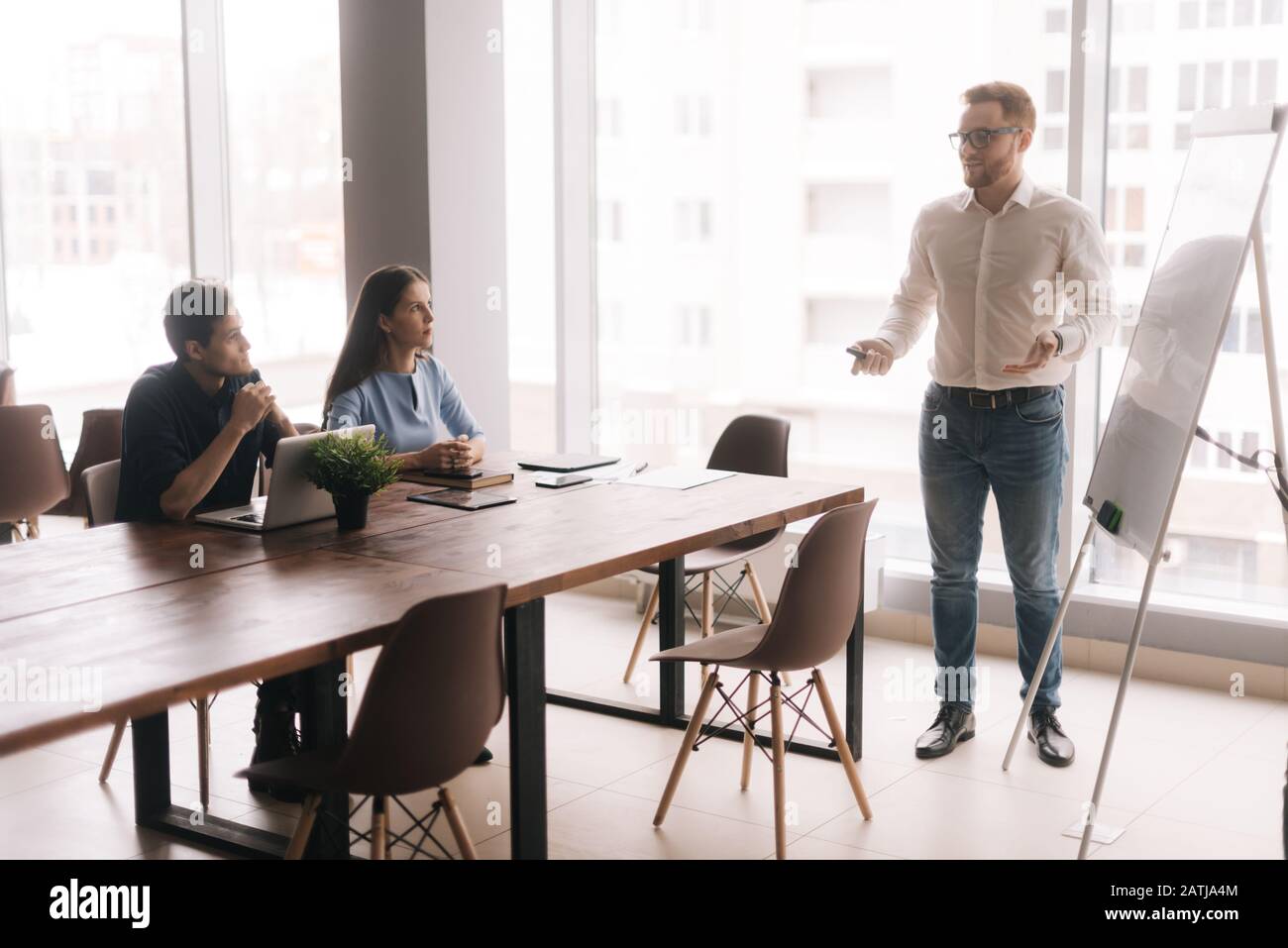 Businessman doing presentation, using whiteboard, explaining to colleagues Stock Photo