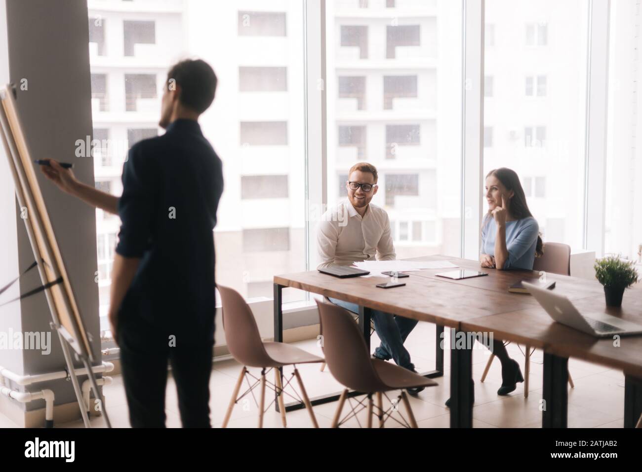 Businessman doing presentation, using whiteboard, explaining to colleagues Stock Photo