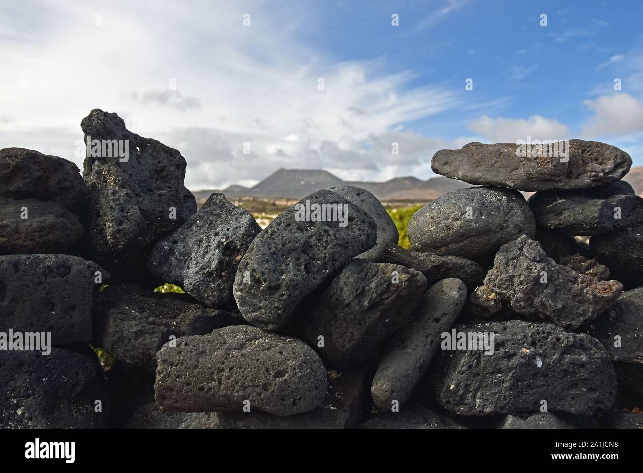 Volcanic stone wall with blurred volcano in background. Lanzarote, Spain. Stock Photo