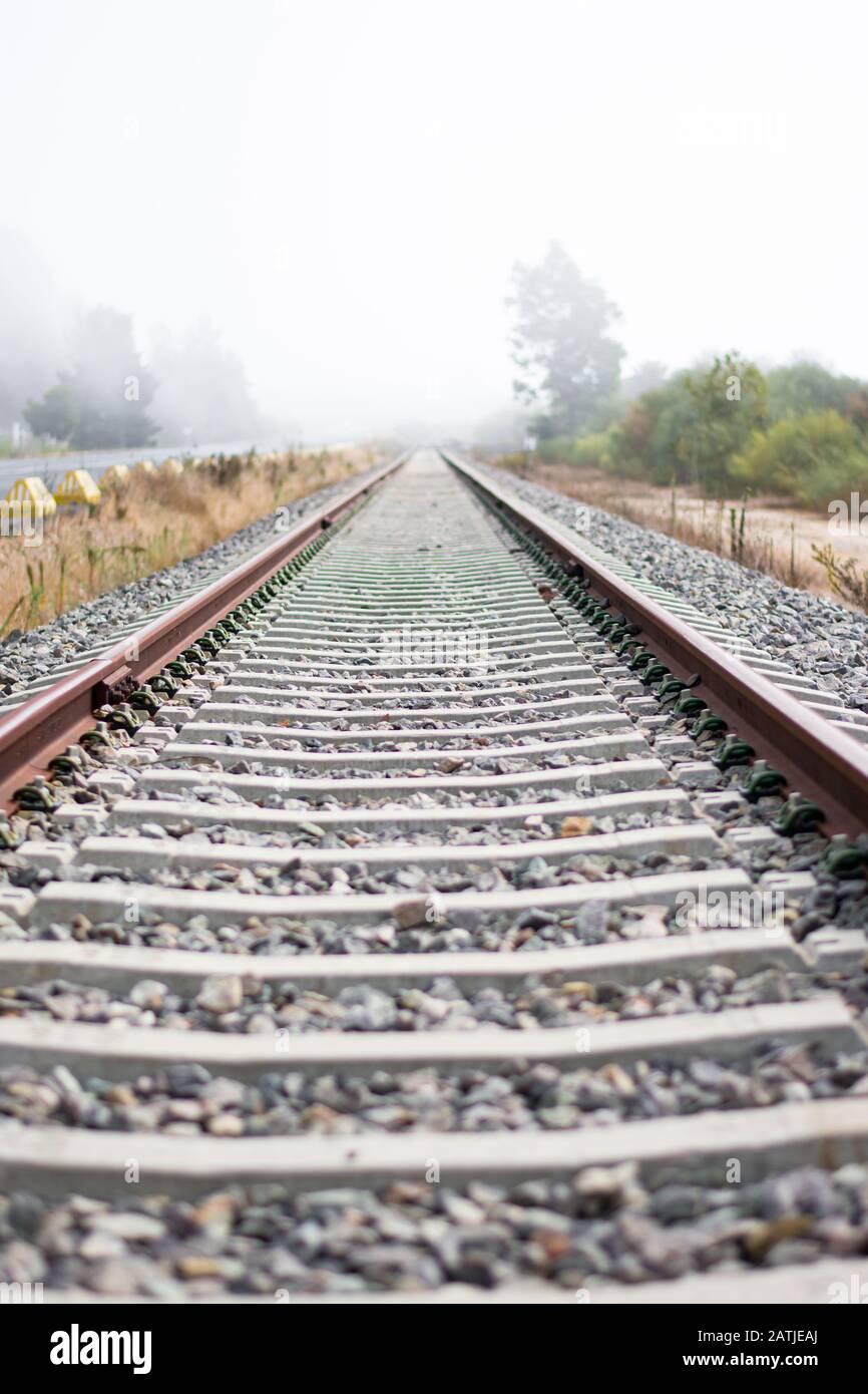 Train tracks creating a vanishing point, with a background that is lost