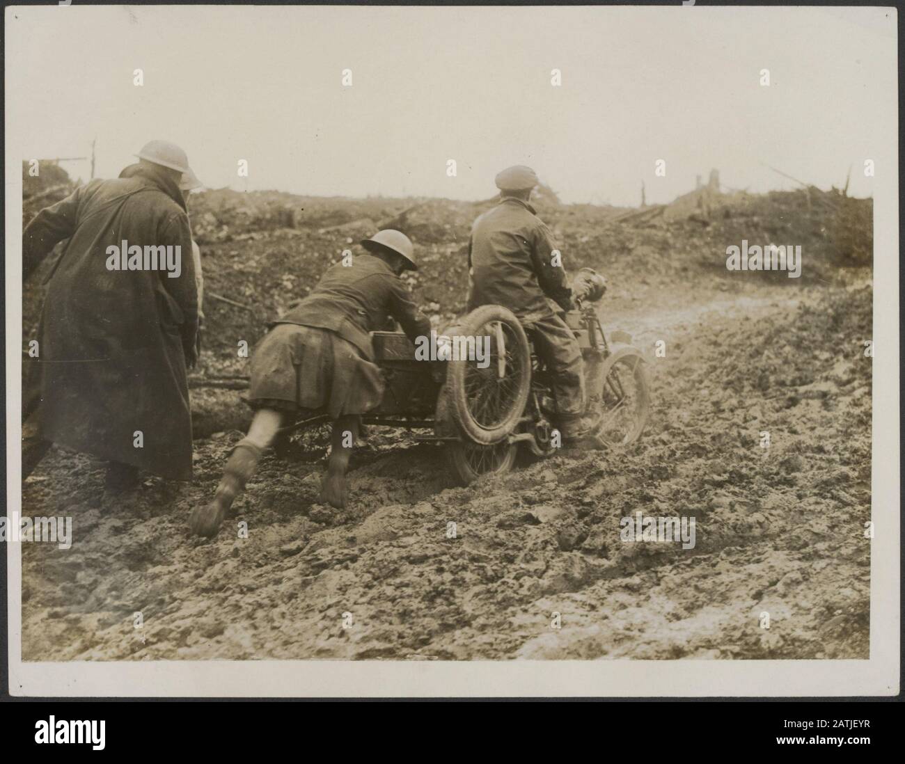 Description: A Canadian Scottie helps a motor machine gun man or a difficulty. Annotation: A Canadian 'Scottie' helps a soldier on a motorcycle with pushing in the mud. Date: {1914-1918} Keywords: WWI, mud, motorcycles, military, transport Stock Photo