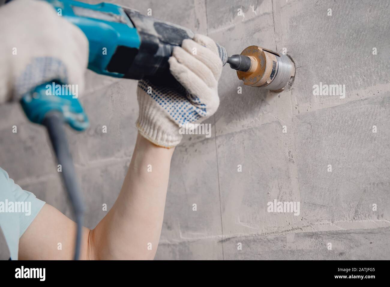 Builder worker pneumatic hammer drills hole in concrete brick wall with