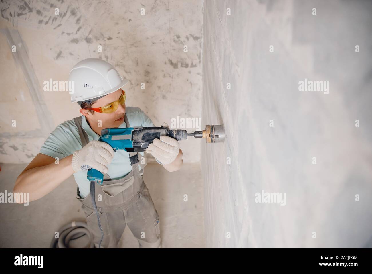 Builder worker pneumatic hammer drills hole in concrete brick wall with