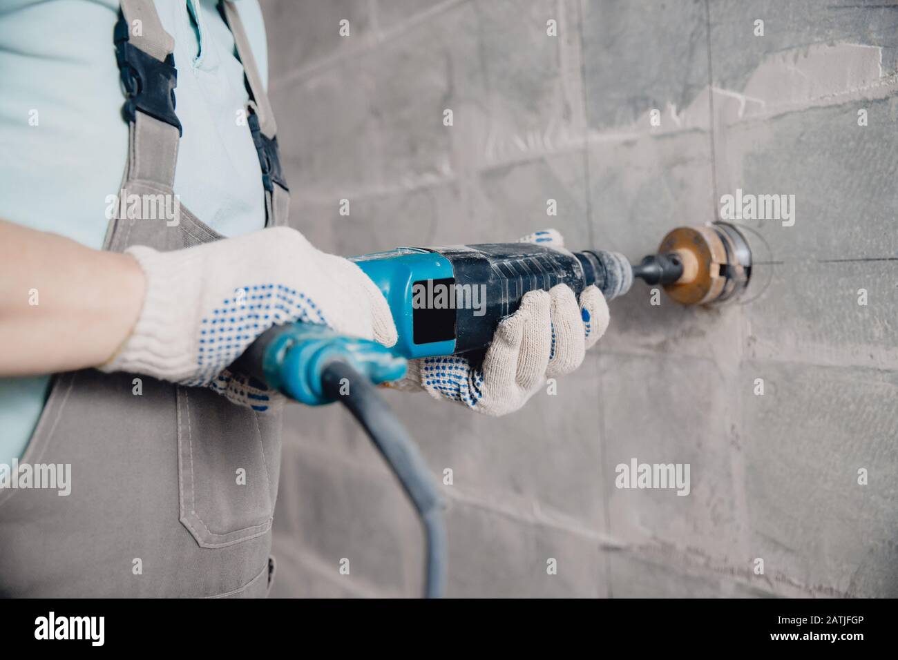 Builder worker pneumatic hammer drills hole in concrete brick wall with