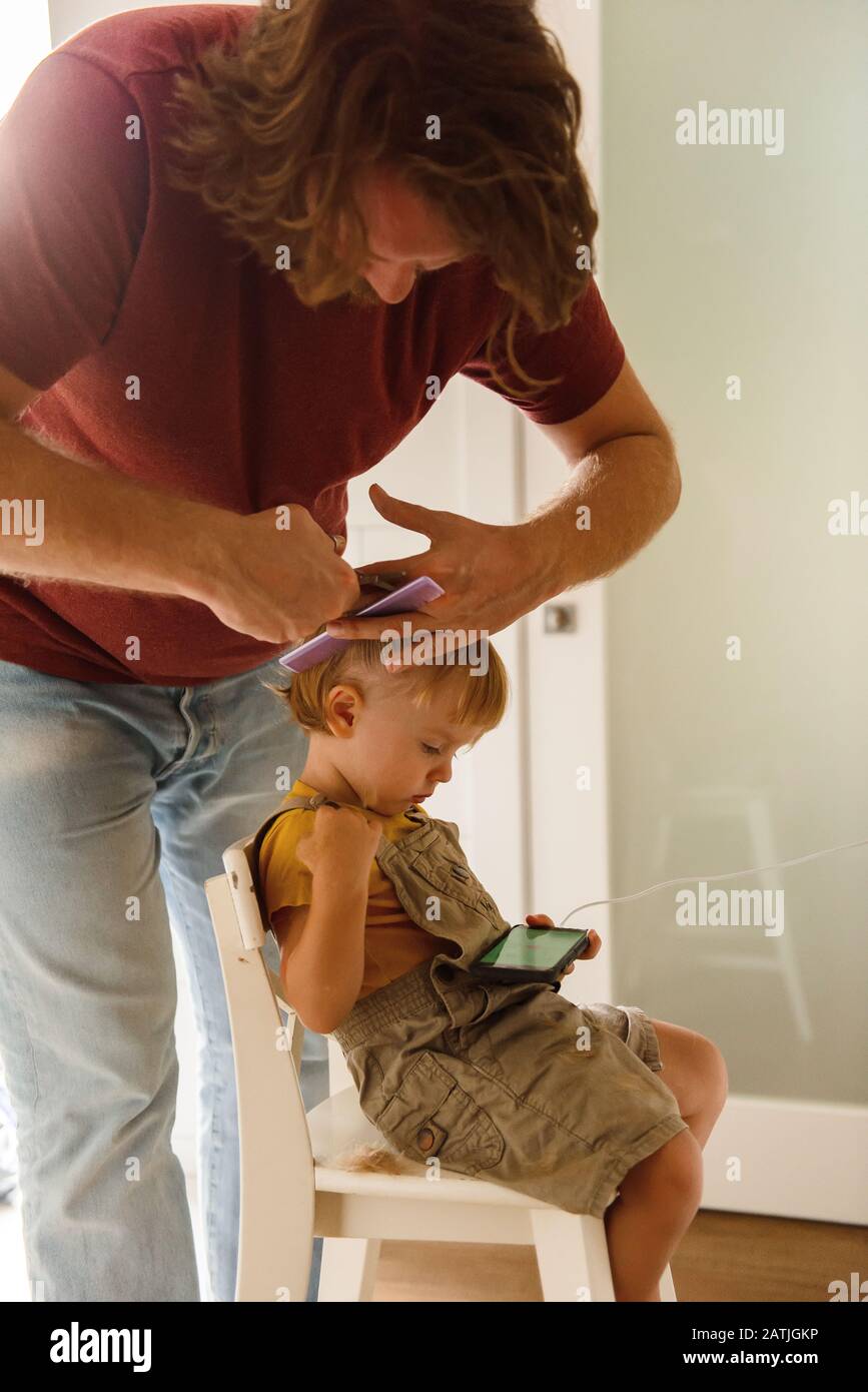 Dad cutting hair to little son Stock Photo
