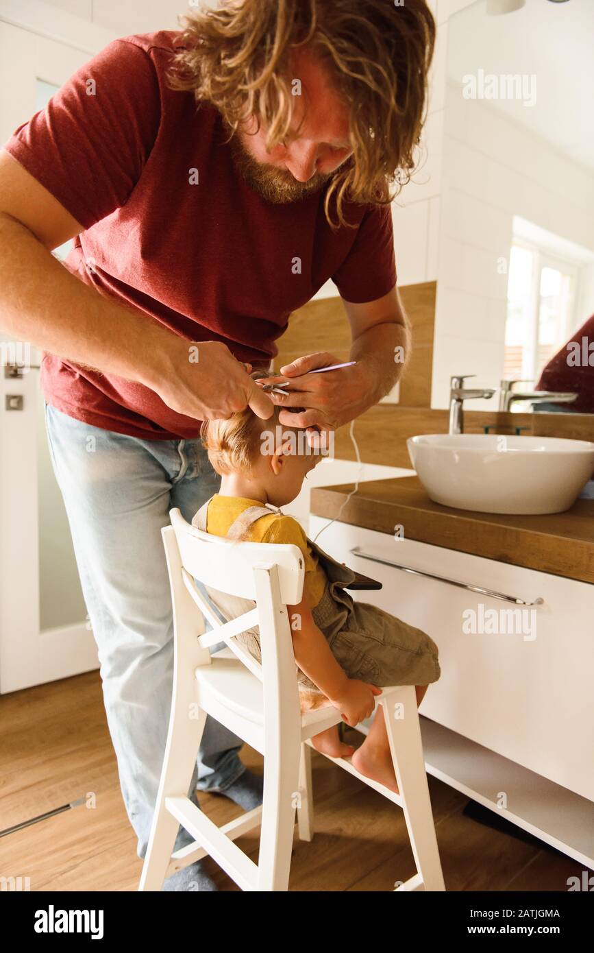 Dad cutting hair to little son Stock Photo