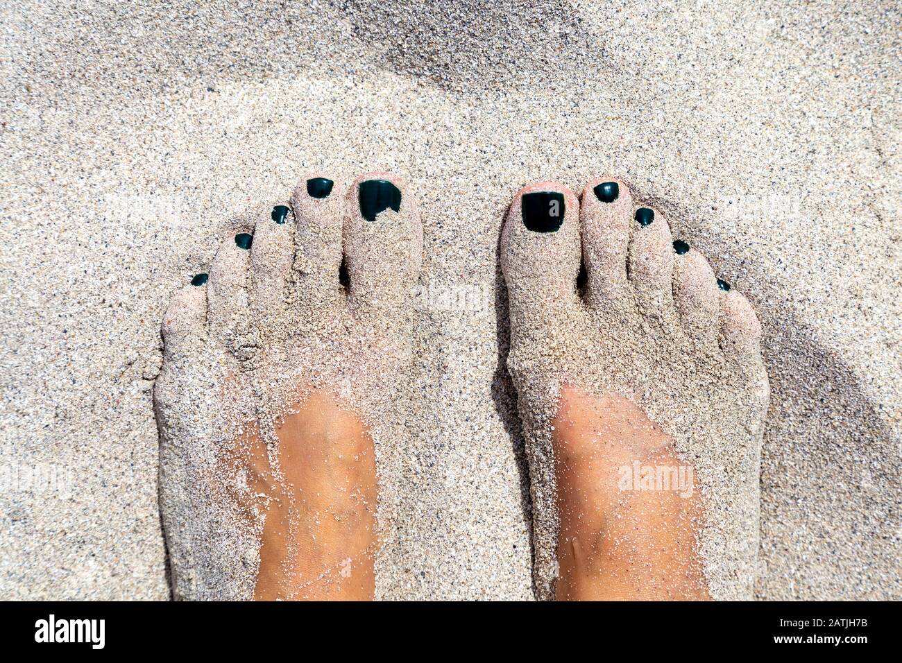 Close-up of a woman's feet covered with sand on the beach Stock Photo