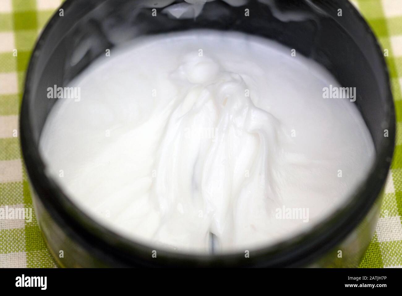 Hair mask in a black plastic container. White body cream in a jar Stock